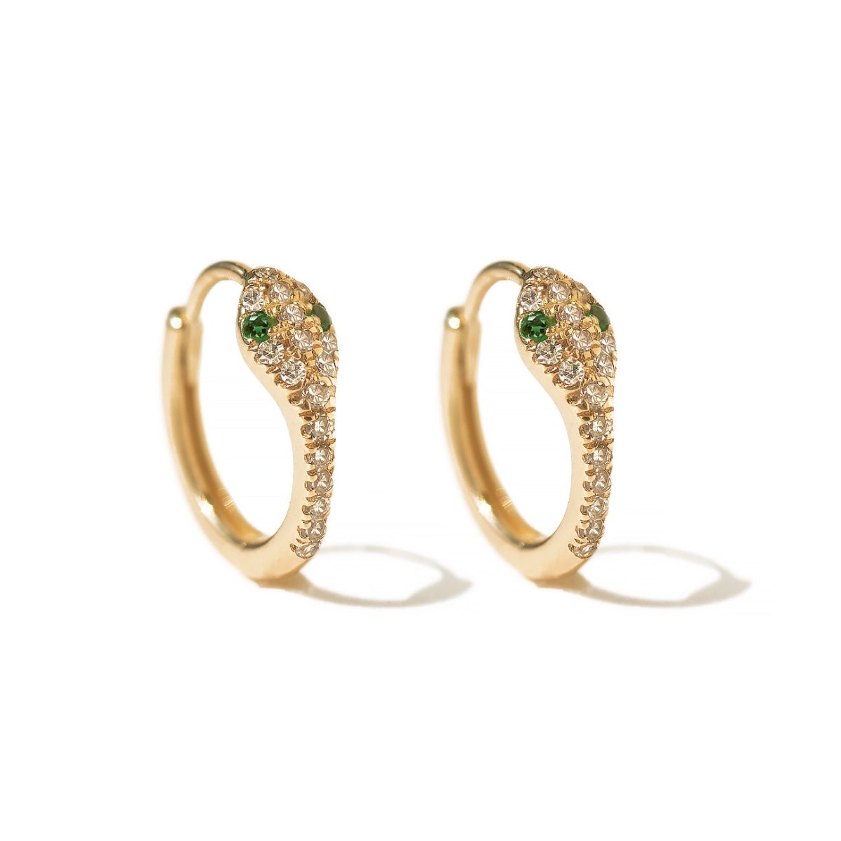 Pair of 14K gold snake huggie hoops paved with natural diamonds and green eye stones, on white background