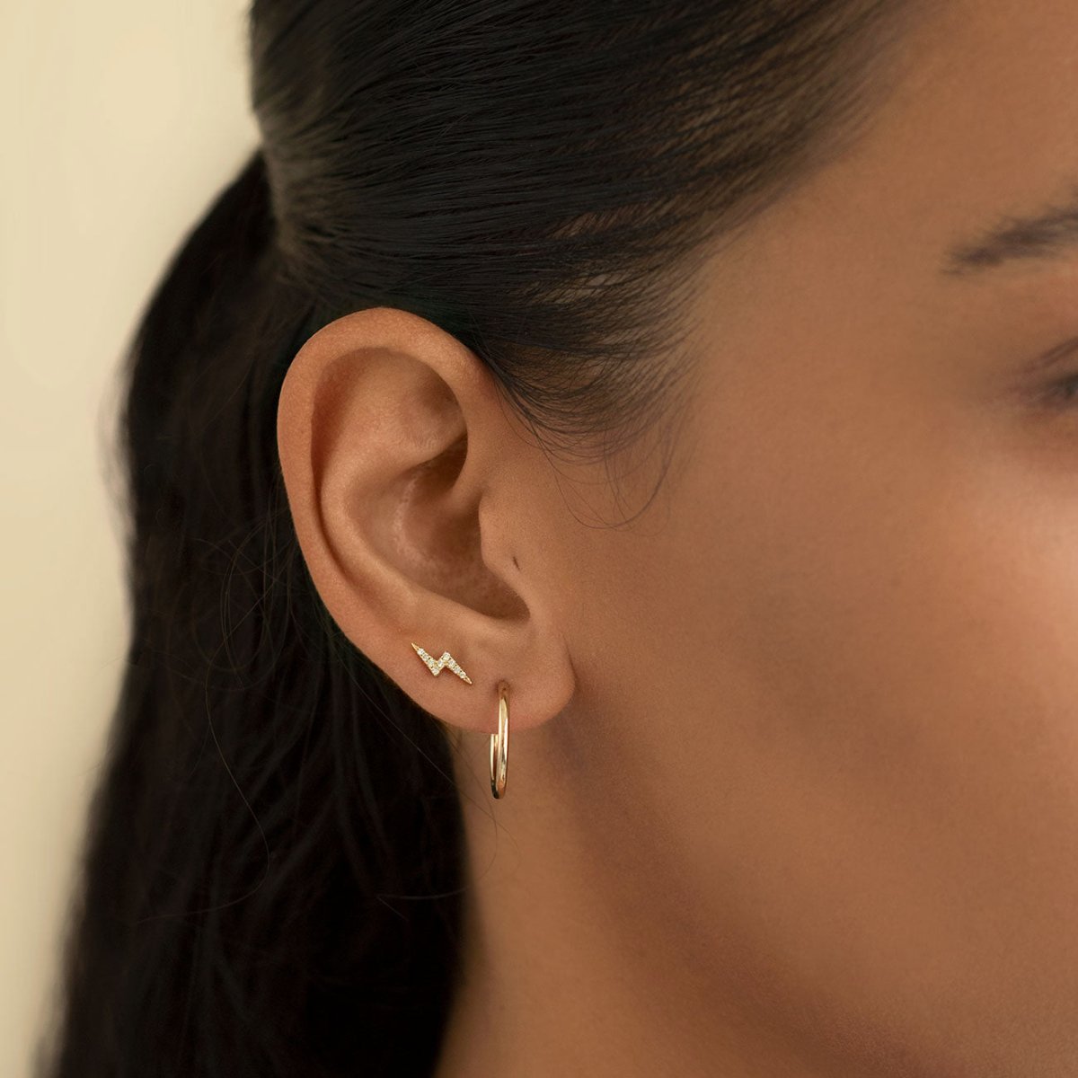 14K gold diamond lightning bolt stud and thin plain hoop shown on a model's ear