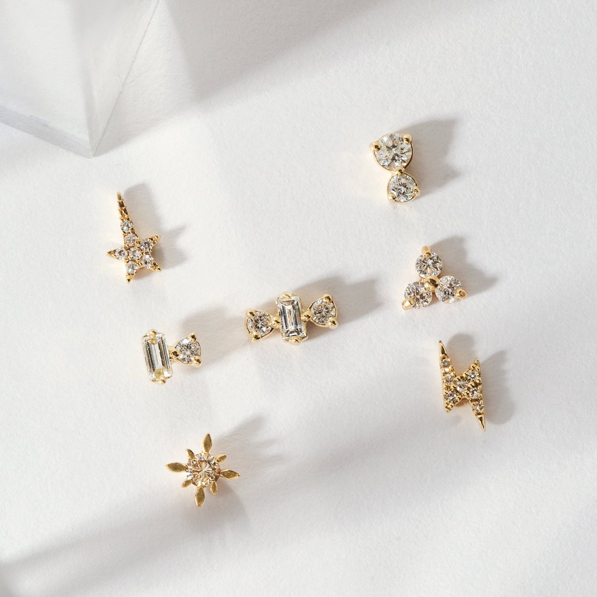 14K gold diamond stud styles including the two-diamond stud, arranged on a white surface