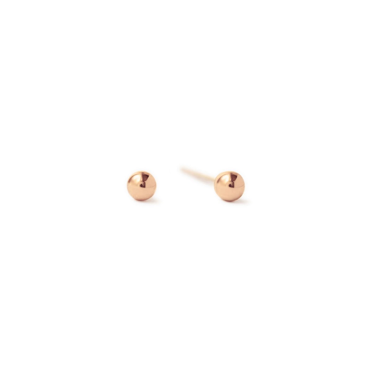 Pair of rose gold-filled tiny ball studs, close-up detail, on a white background