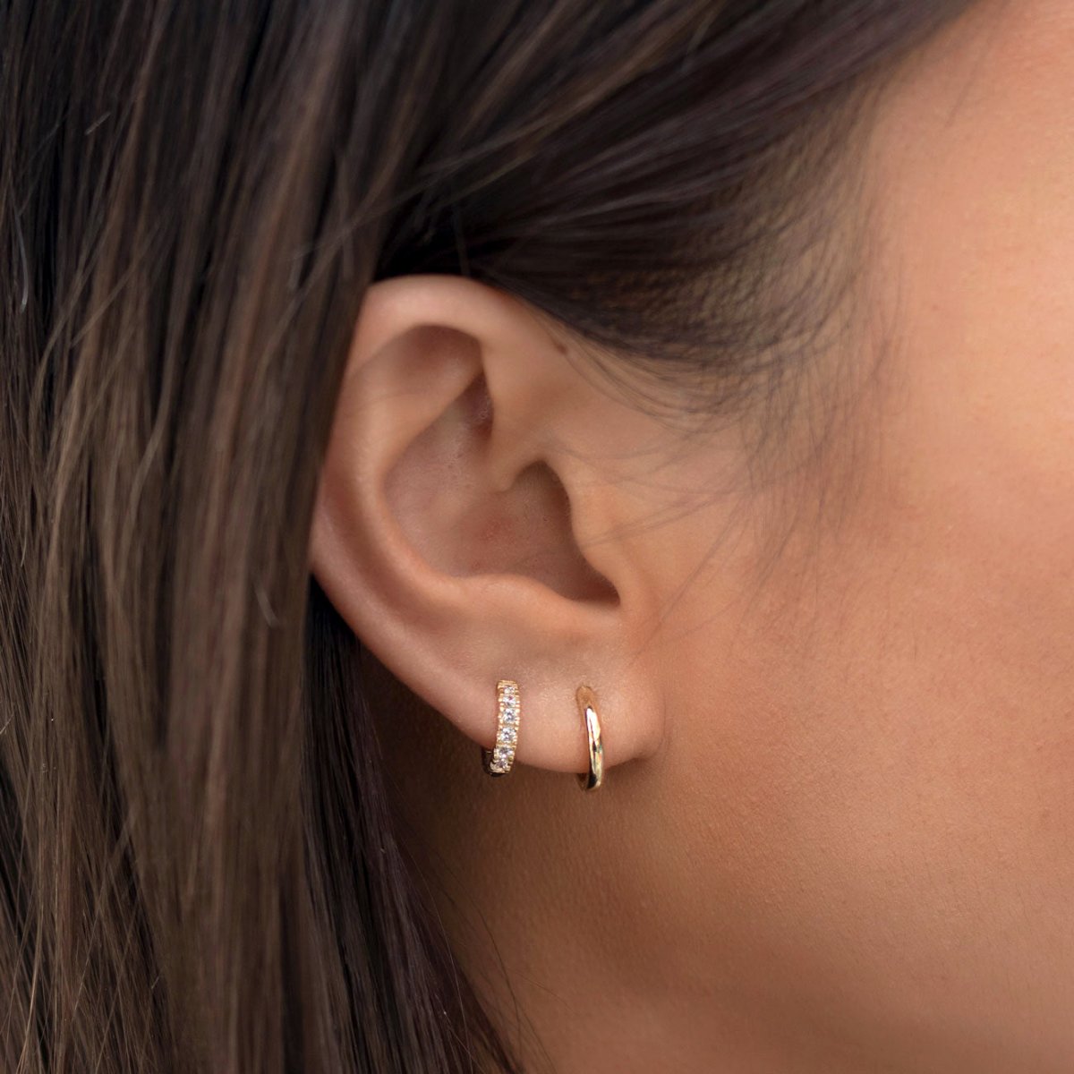 14K gold diamond pave huggie hoop and thin plain hoop shown on a model's lobe