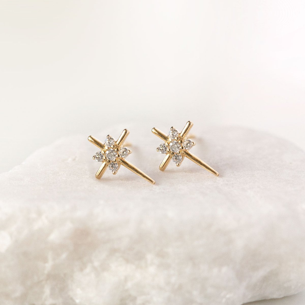 14K gold thin cross stud earrings with clear zirconia stones, angled close-up on a white background