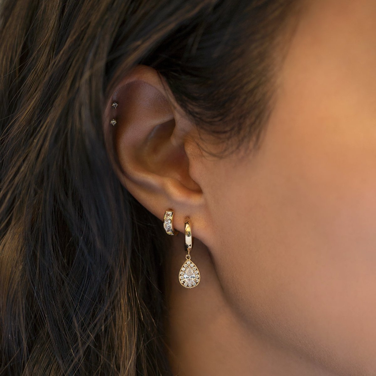 Gold vermeil white zirconia huggie hoop with a teardrop charm shown on a model's lobe