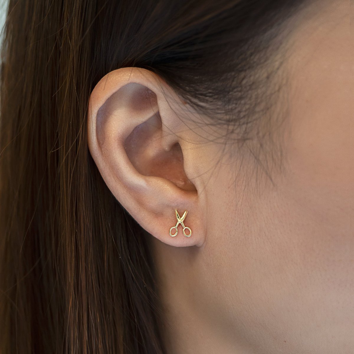 14K gold scissor stud earring shown on a model's lobe