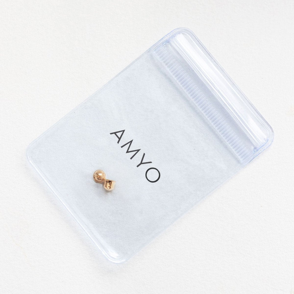 14K rose gold screw-back earring back in a branded pouch, on a cream background