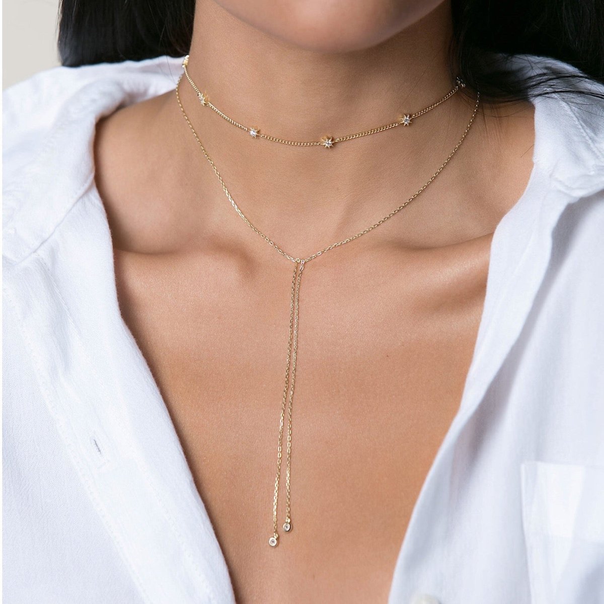 Gold vermeil starburst station choker with white zirconia stars, layered and shown on a model's neck