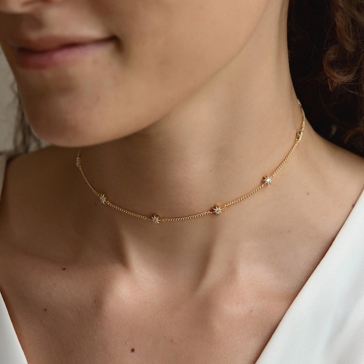 Gold vermeil starburst station choker with white zirconia stars, shown close on a model's neckline