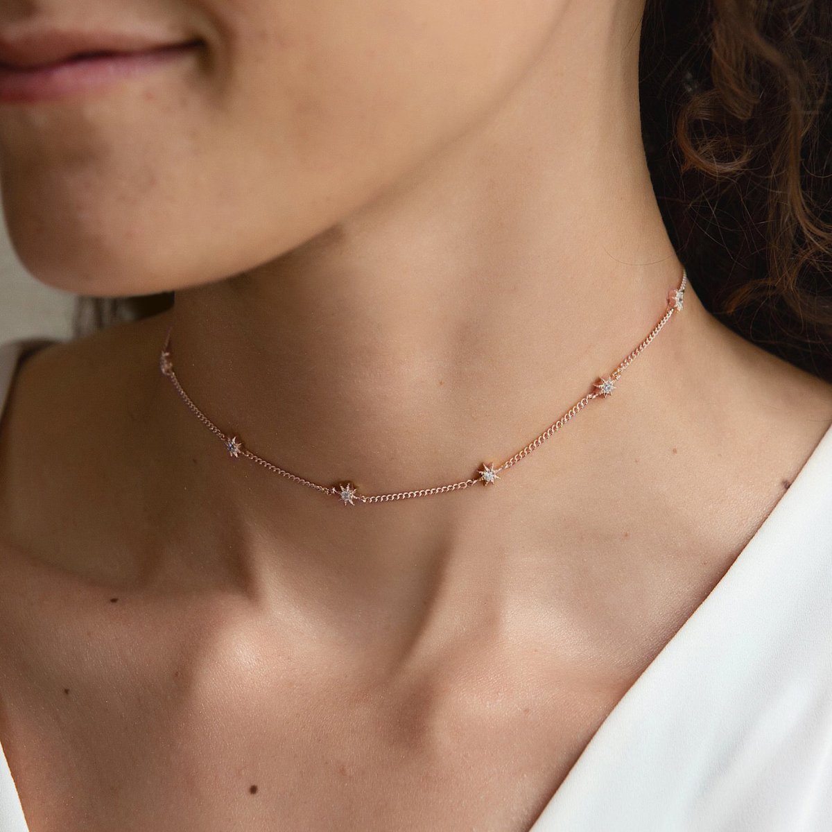 Rose gold vermeil starburst station choker with white zirconia stars, shown on a model's neck