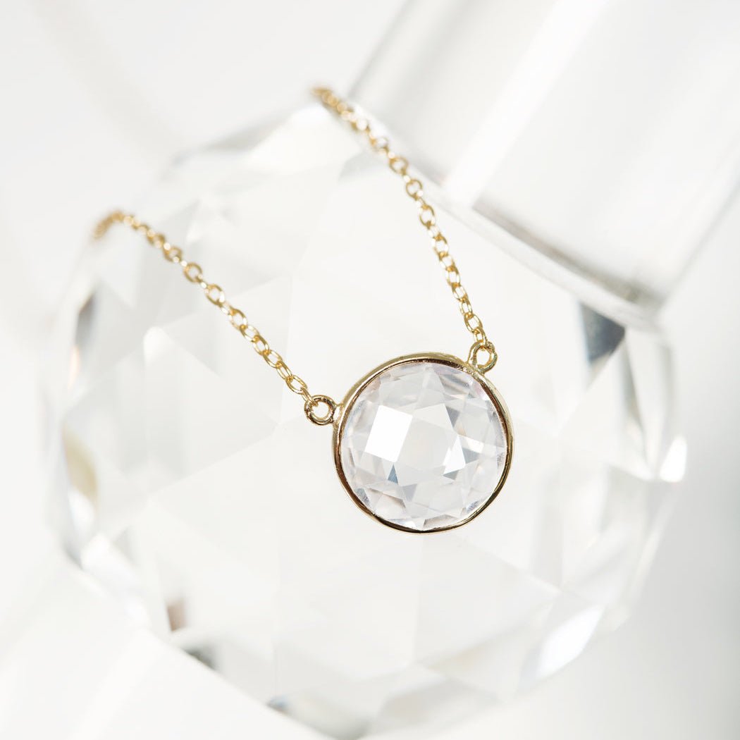 Gold vermeil necklace with a round faceted clear stone pendant, close-up detail on crystal