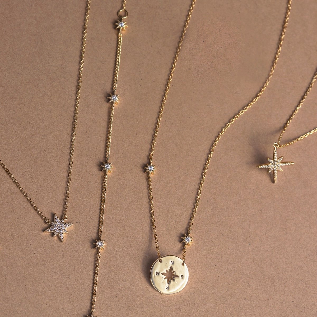 Gold vermeil star jewelry set with pavé star studs and a star station chain, on tan
