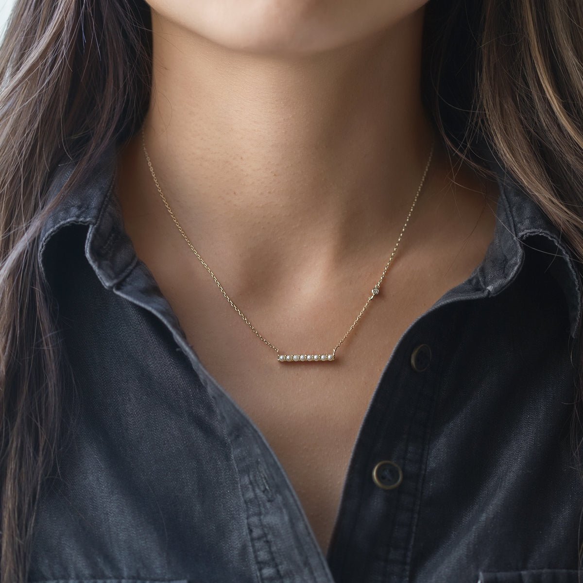 Sterling silver pearl bar necklace shown on a model's neckline over a dark shirt