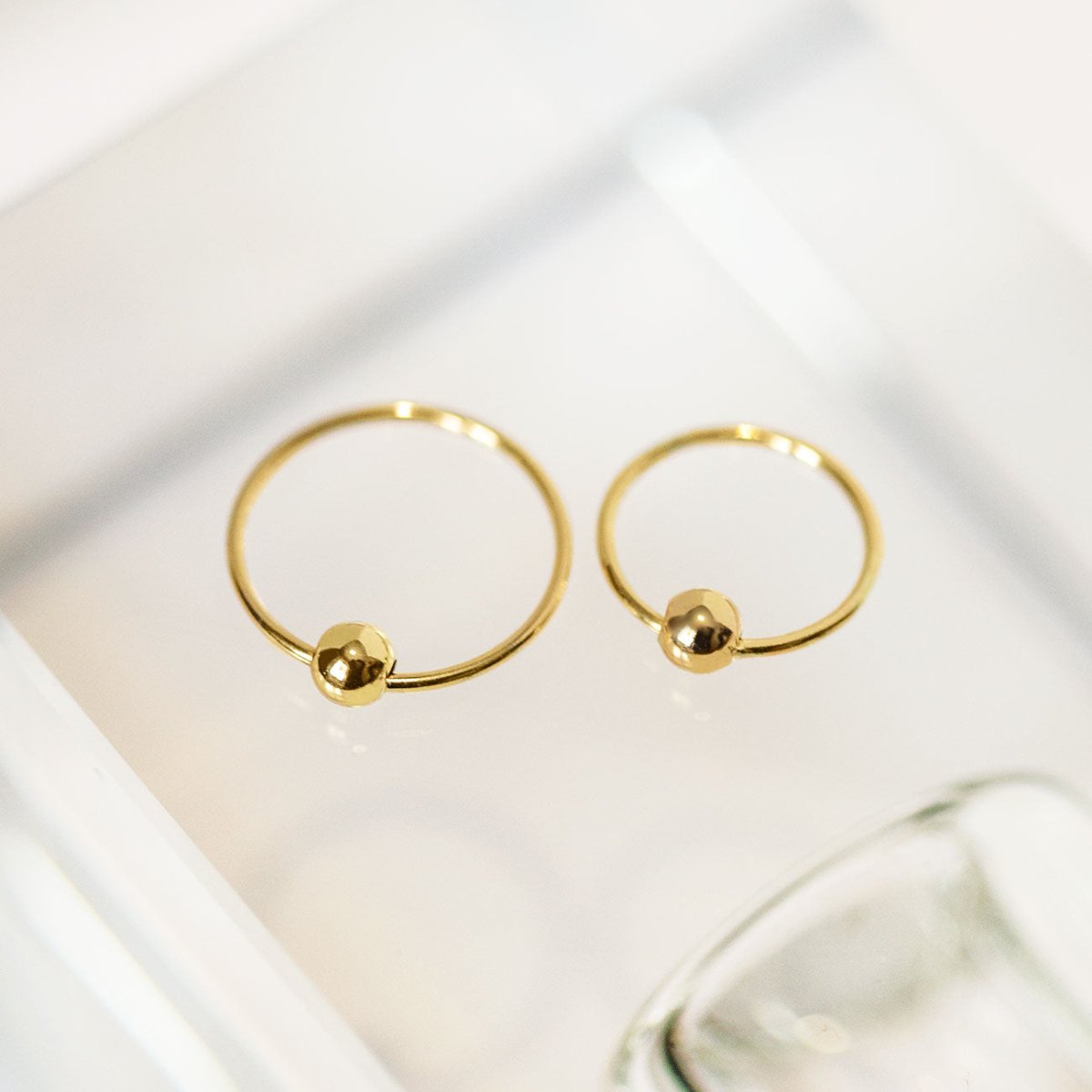 14K gold captive bead ring with a single bead, close-up detail on a white background