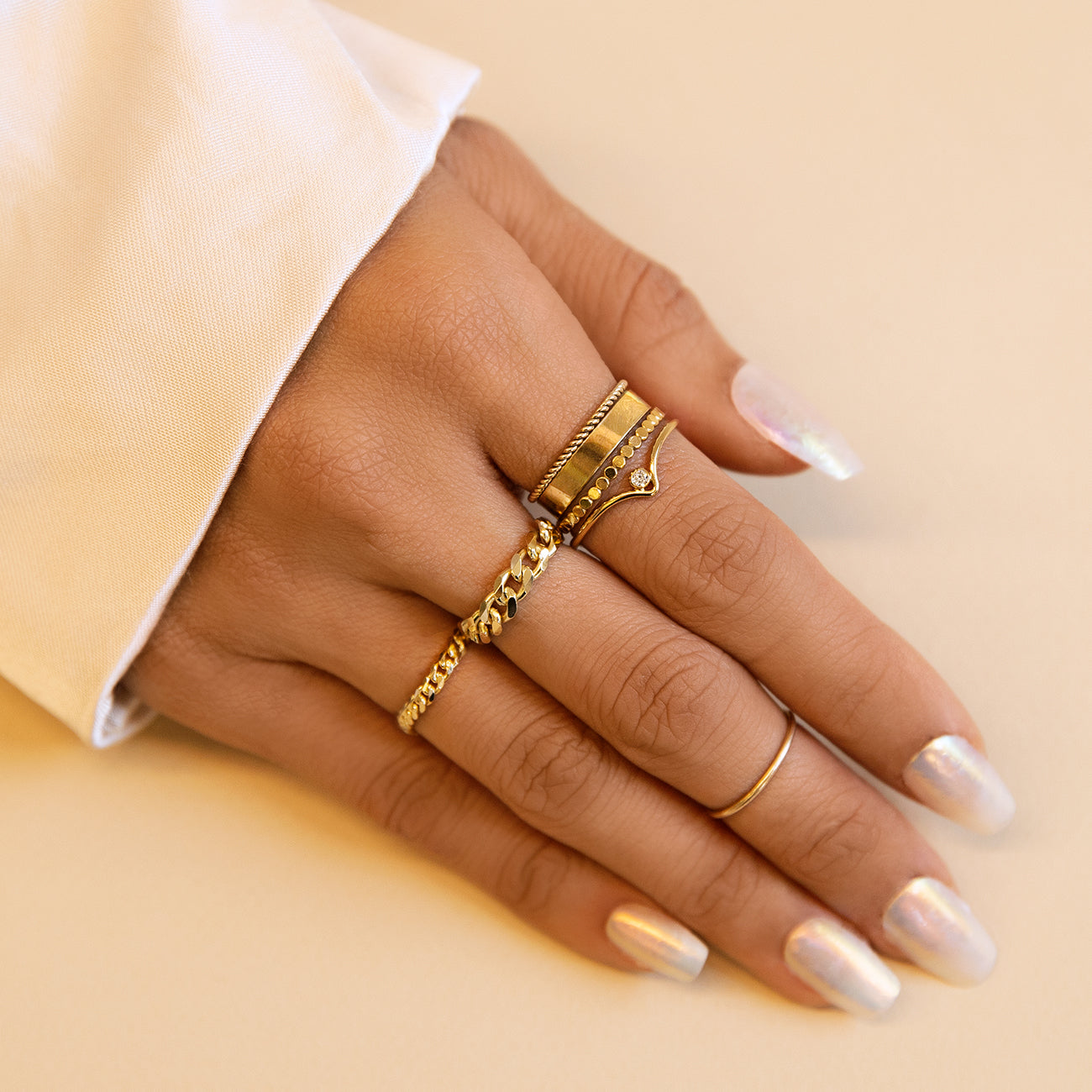 Gold vermeil cigar band ring in a stack, shown on a model's hand on a cream background