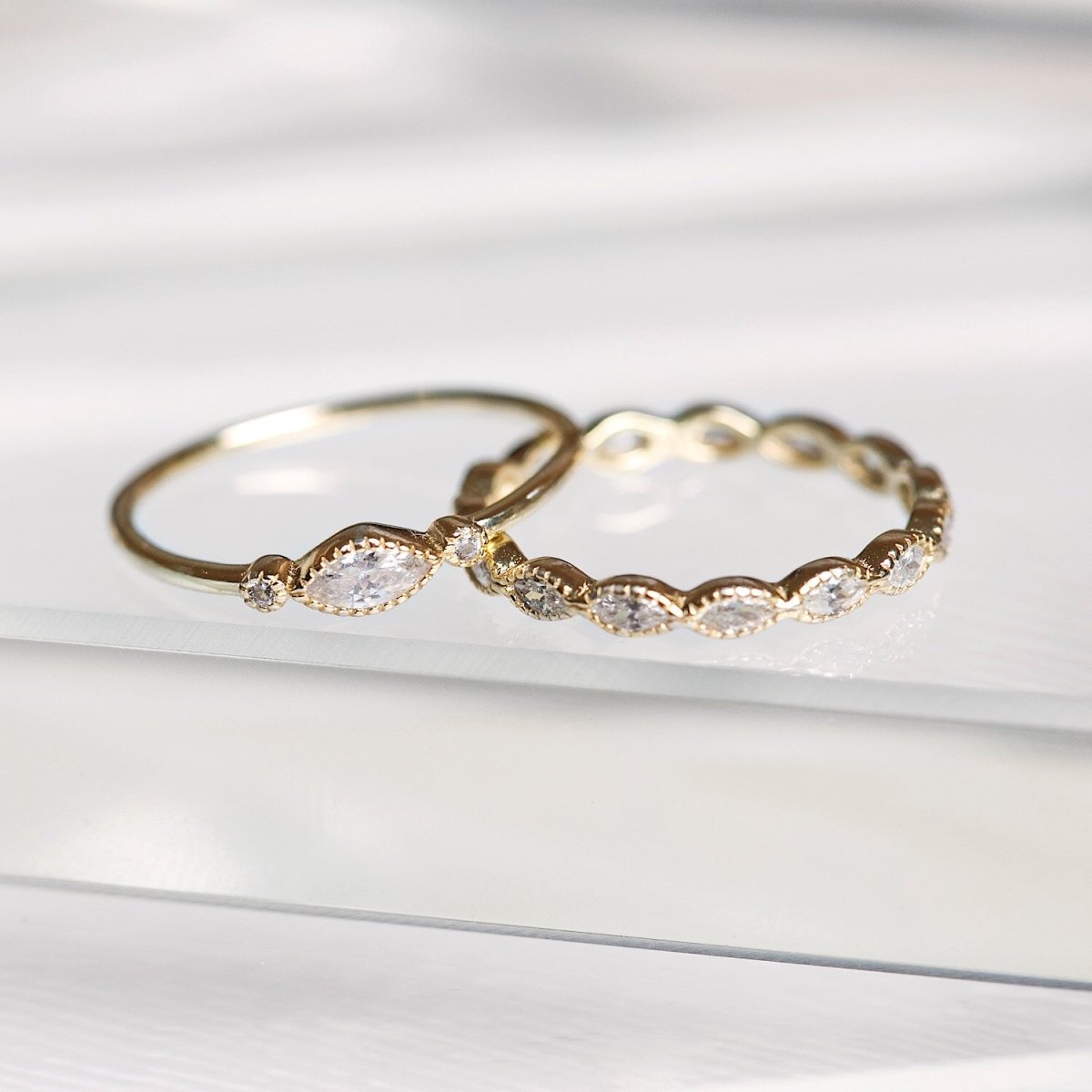 Gold vermeil marquise white zirconia eternity band ring shown beside a single-stone band, close-up detail